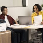 Due persone in ufficio accanto alla stampante a colori Xerox® C410