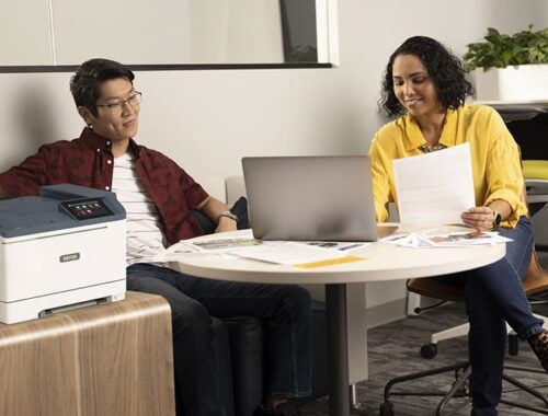 Due persone in ufficio accanto alla stampante a colori Xerox® C410
