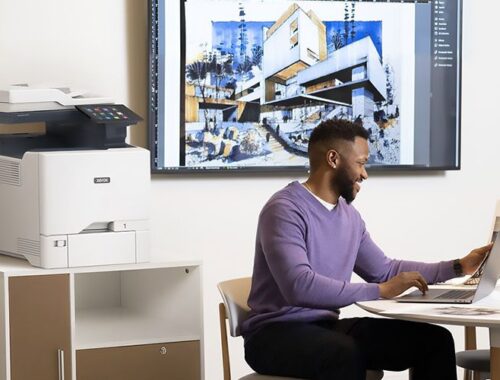 Uomini che lavorano su un computer portatile davanti a una stampante multifunzione a colori Xerox® VersaLink® C415